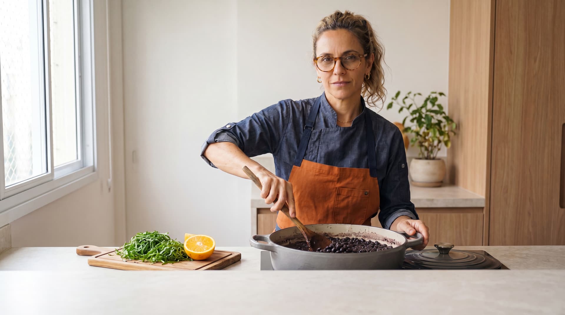 Chef Juliana in a bright, modern São Paulo kitchen, the everyday plate of rice, beans, and greens on the counter before her